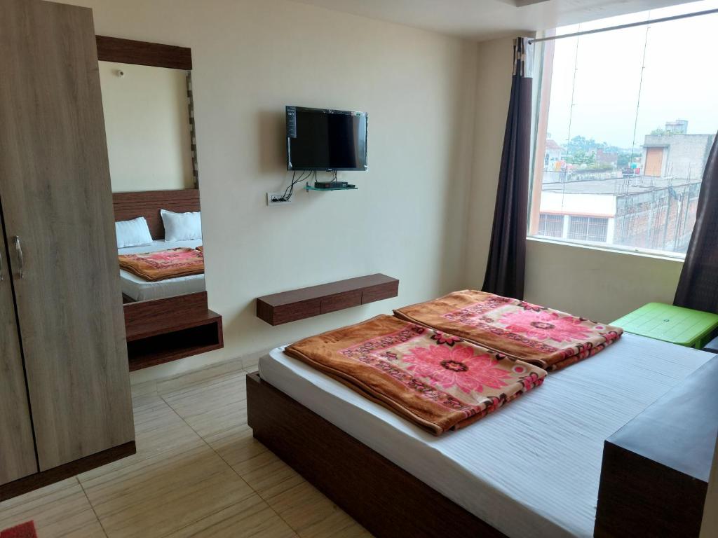 - une chambre avec 2 lits et une télévision murale dans l'établissement HOTEL SATYAM PALACE, à Deoghar