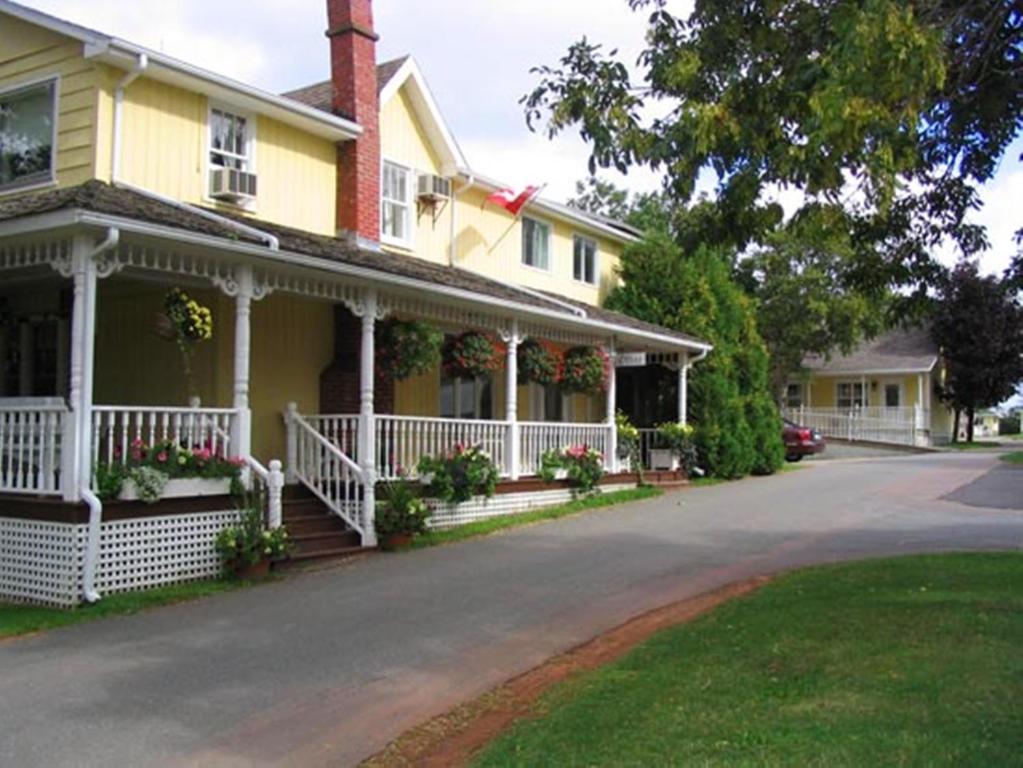 a yellow house with flowers on the front porch at Shining Waters Country Inn in Cavendish