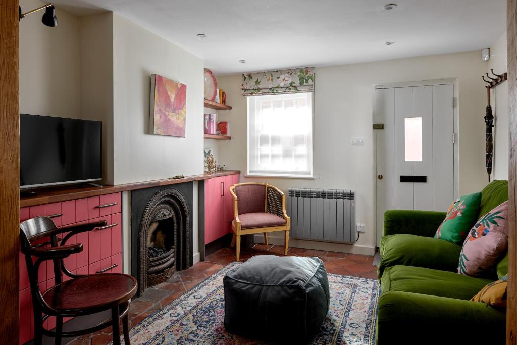 a living room with a green couch and a fireplace at Pearls Cottage in Farnham