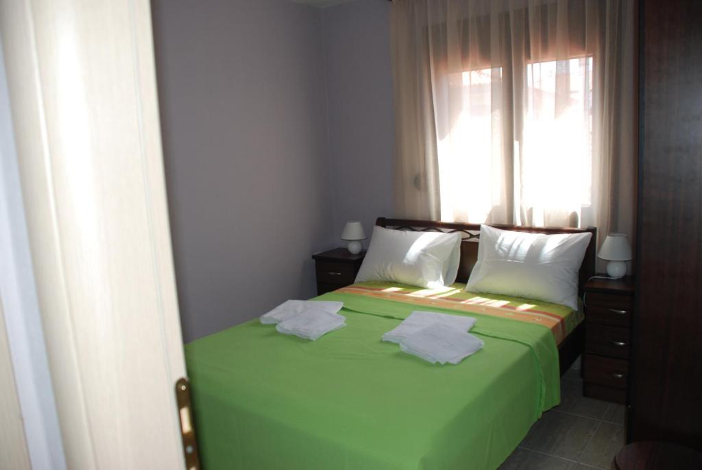 a bedroom with a green bed with a window at Marianna Apartments in Nea Roda