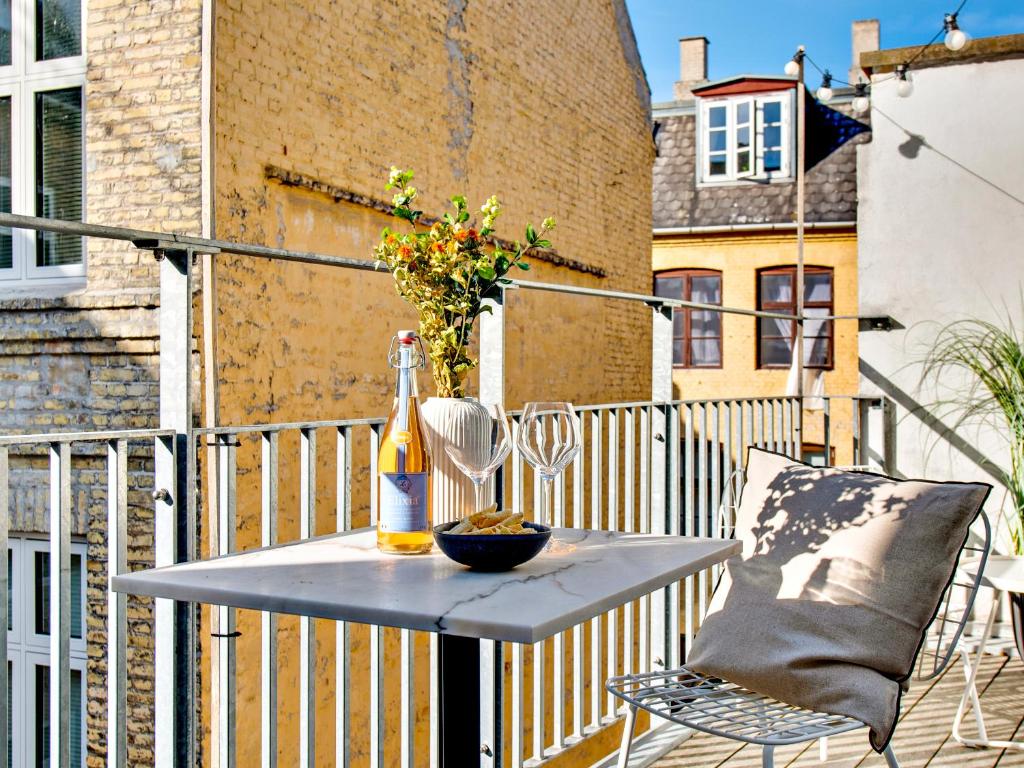 a table with a bottle and glasses on a balcony at Sanders Leaves - Charming Three-Bedroom Apartment In Downtown Copenhagen in Copenhagen
