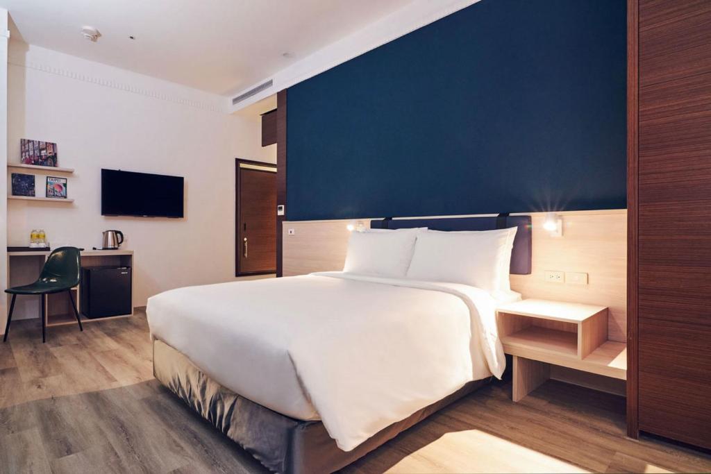 a bedroom with a large bed with a blue wall at CHECK inn Select Taipei Nangang in Taipei