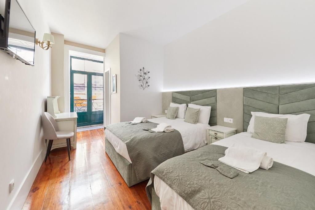 a hotel room with two beds and a window at A Portuguesa Guest House in Porto