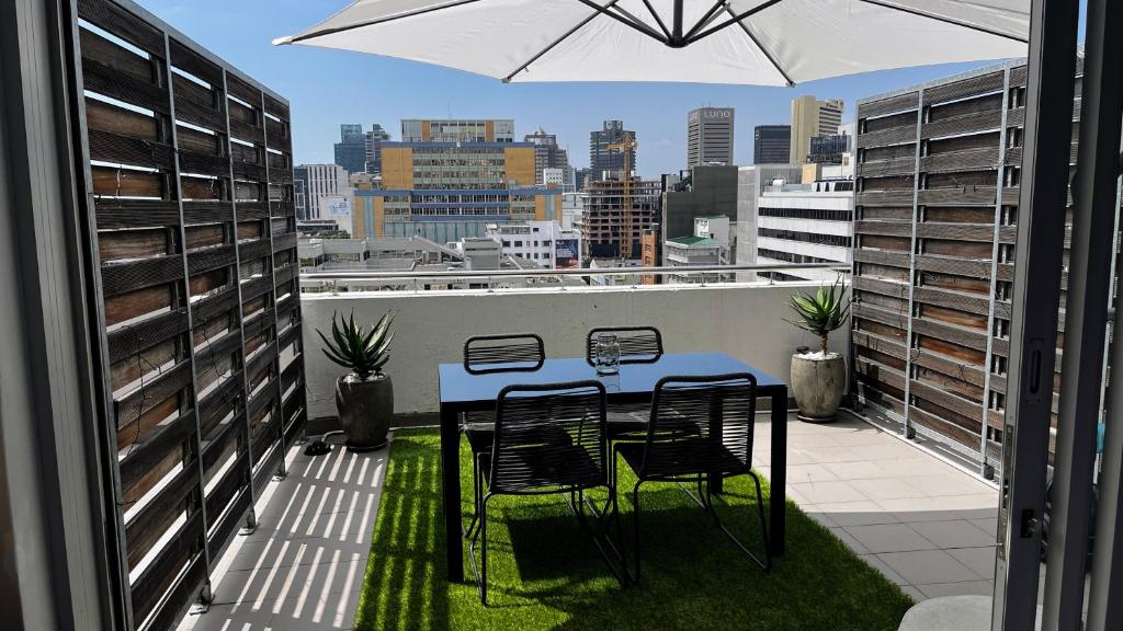 uma mesa e cadeiras numa varanda com um guarda-sol em Modern Luxury Studio with Breathtaking City Views - No Load Shedding em Cidade do Cabo