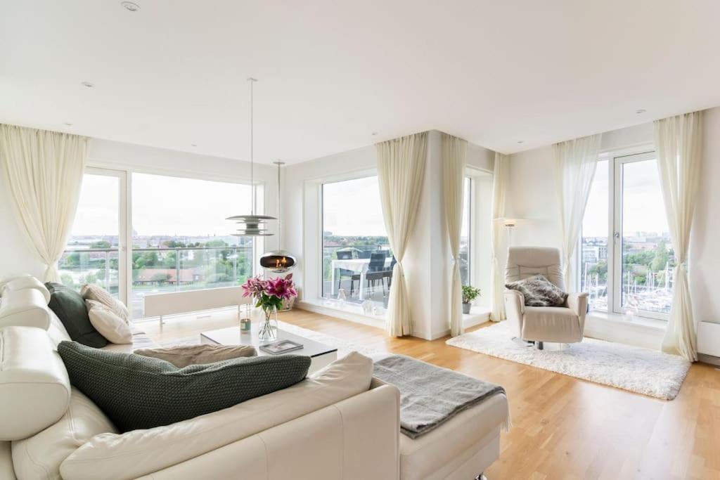 Penthouse with amazing views of Copenhagen! في كوبنهاغن: غرفة معيشة مع أريكة بيضاء ونوافذ كبيرة