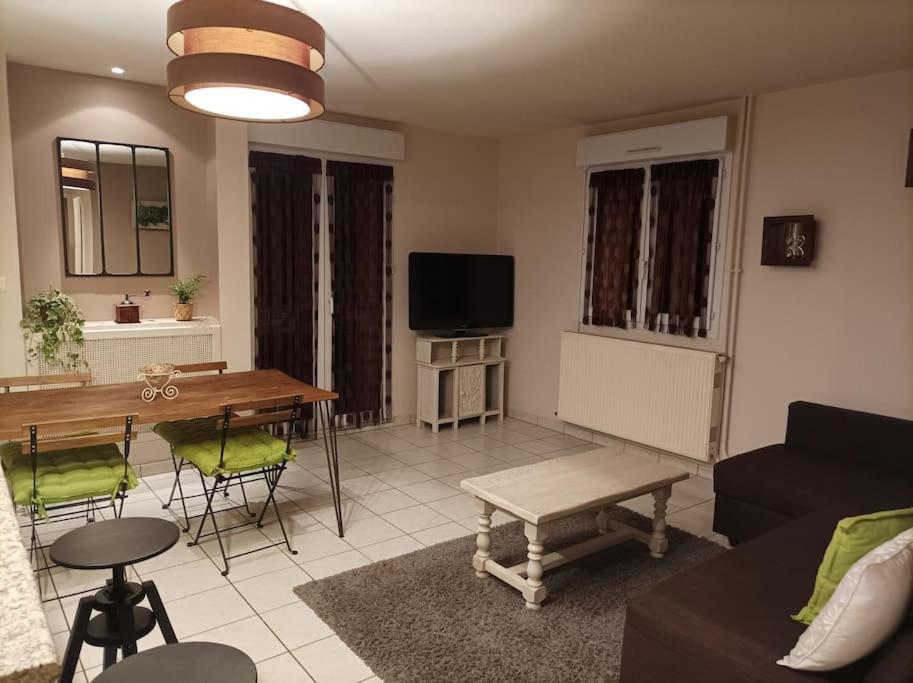 een woonkamer met een bank en een tafel bij Ecully, appartement au calme de 50m². in Écully