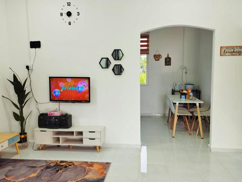 sala de estar con TV en una pared blanca en Homestay Berkat D'sawah Tasek Berangan Pasir Mas, en Pasir Mas
