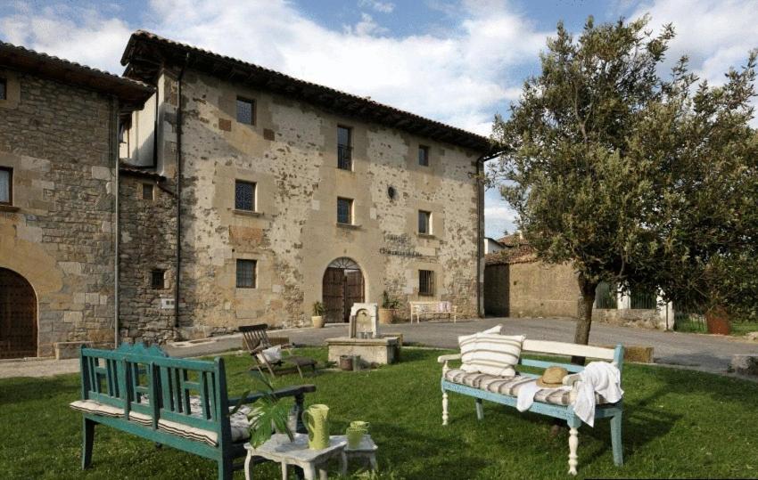 two benches sitting in the grass in front of a building at Hotel El Secreto de Ollo in Ollo