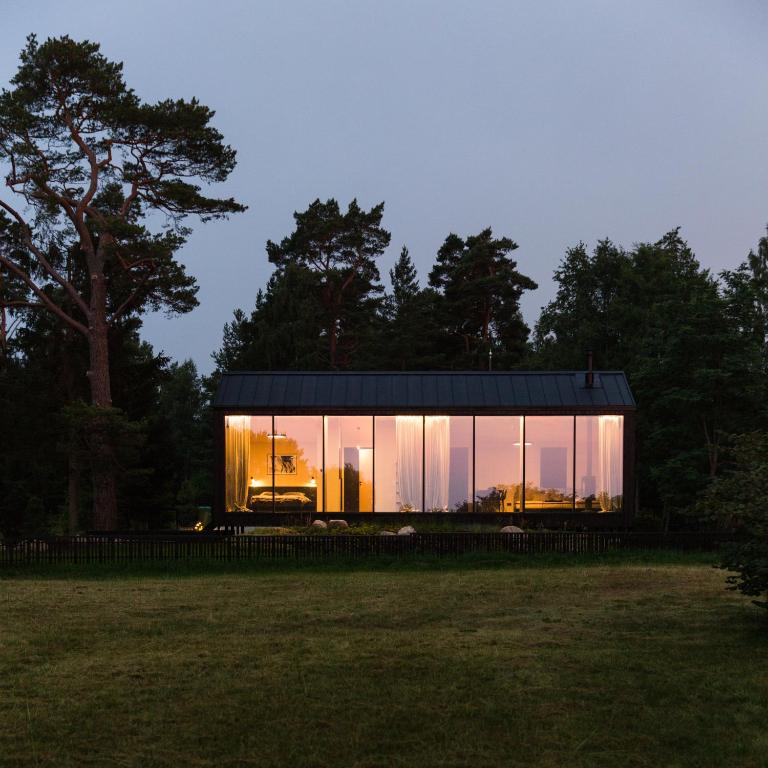 a glass house with a black roof in a field at MAAJO Boutique Hotel in Valgalciems