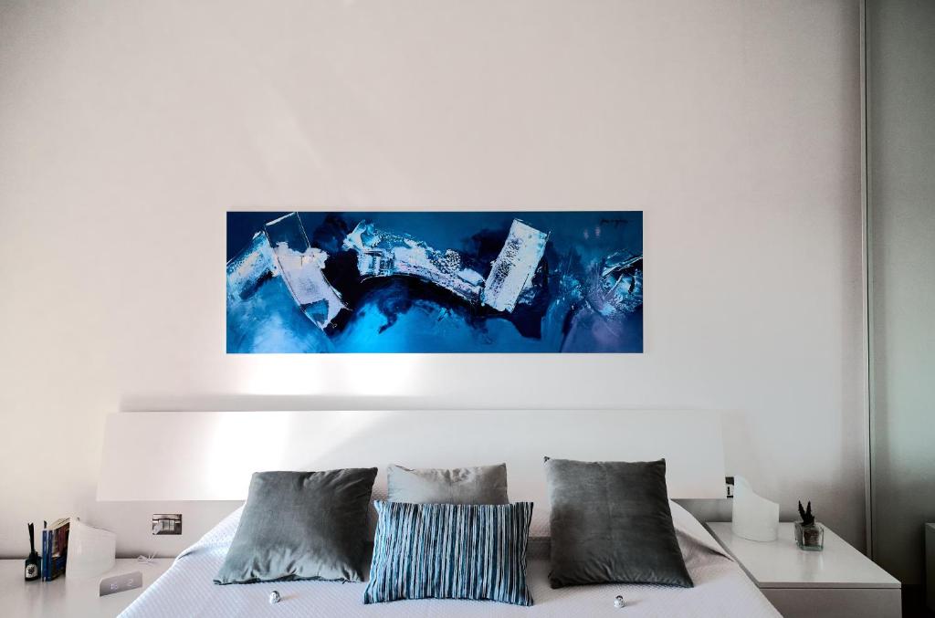 sypialnia z białym łóżkiem i niebieskim obrazem na ścianie w obiekcie San Siro Design Apartment w Mediolanie