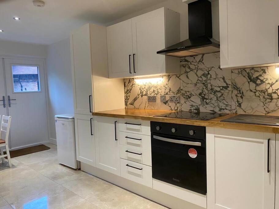 a kitchen with white cabinets and a black oven at The Lodge in Royal Tunbridge Wells