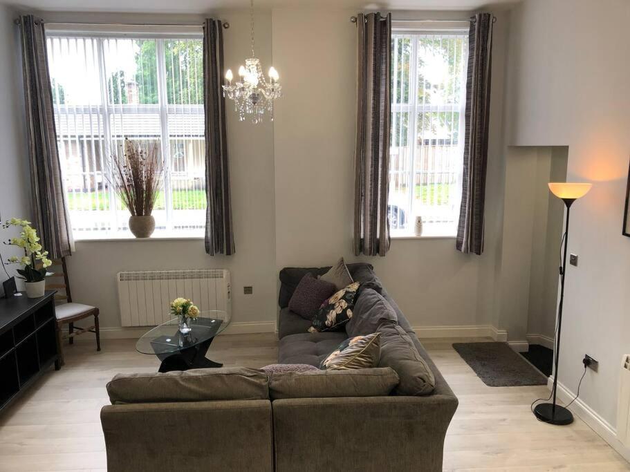 sala de estar con sofá y 2 ventanas en Central Newark Apartment 1 St Mary’s Rooms, en Newark-on-Trent