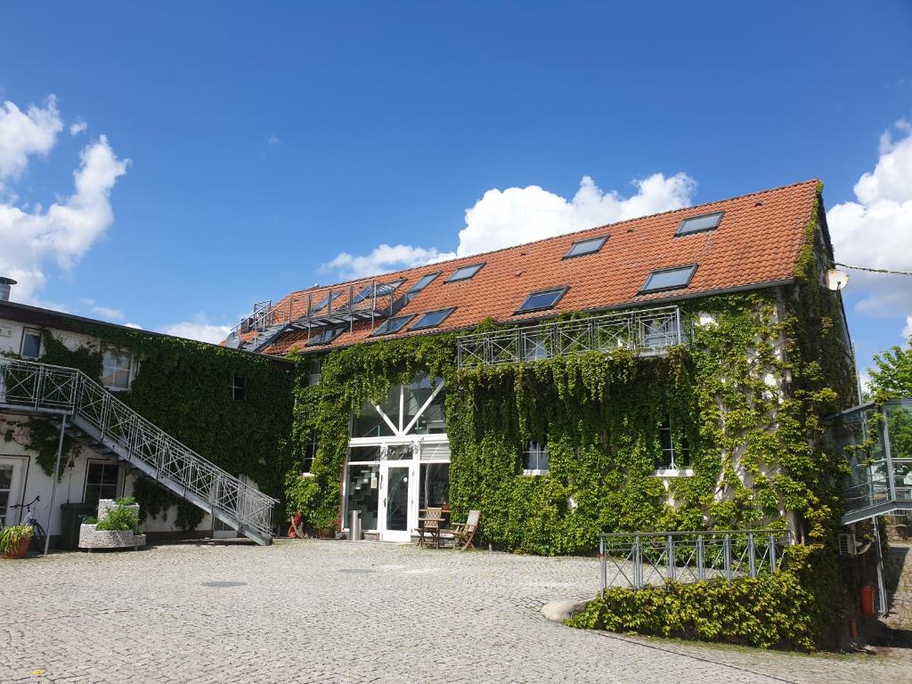 a building covered in green ivy with a staircase at Hotel Bördehof in Barleben