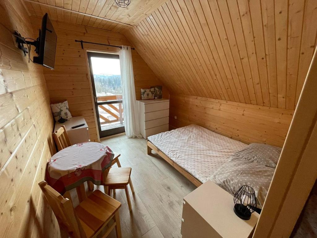 Habitación en el ático con cama, mesa y sillas en Agroturystyka Wudarsówka, en Sokolec