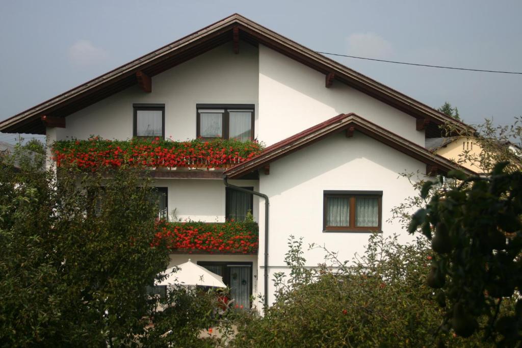 Haus Stuttgart في Obernberg am Inn: منزل أبيض وبه زهور حمراء