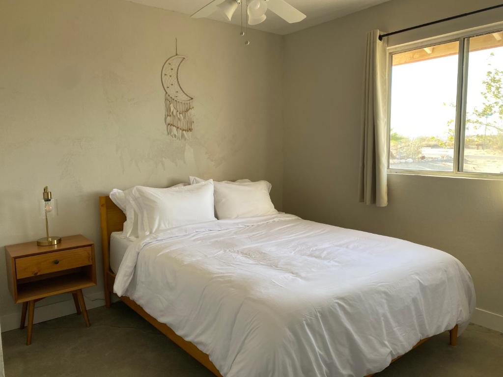 a bedroom with a bed with white sheets and a window at Casa Del Desierto - Panoramic Views - Pet Friendly - Fire Pit in Joshua Tree