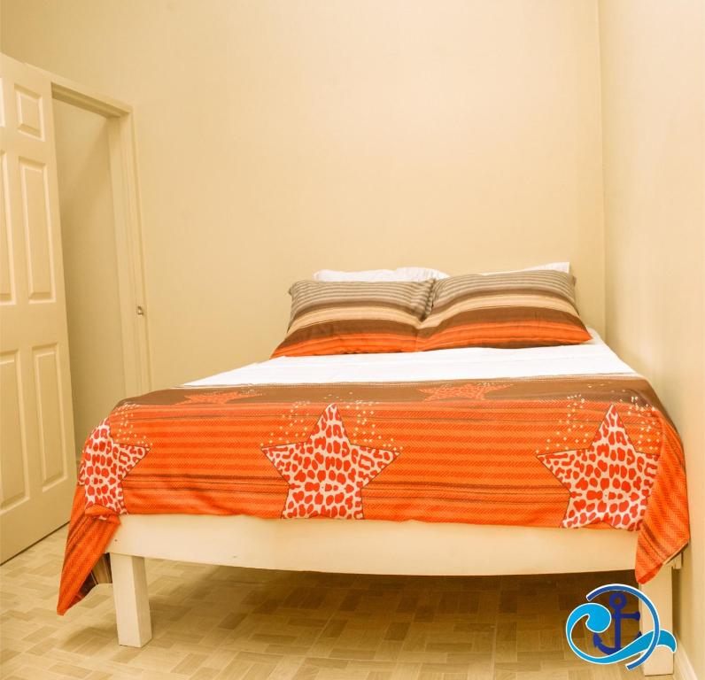 ein Bett mit einer orangefarbenen und weißen Decke drauf in der Unterkunft Mariner Motel in Bridgetown