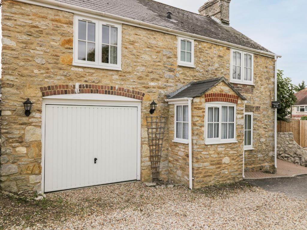 a stone house with a white garage at Fisherbridge Cottage in Weymouth