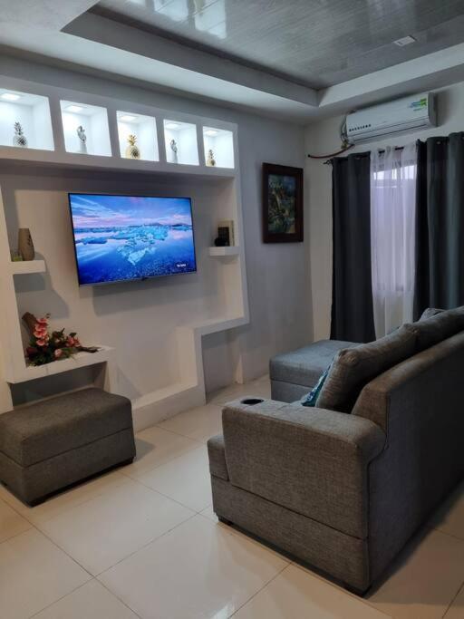a living room with a couch and a flat screen tv at Pura vida apartament 5 min near aiport NO PARKING SITE in Alajuela City