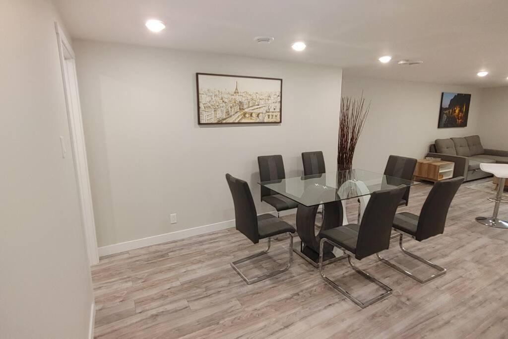 a dining room with a glass table and black chairs at Beautiful 2 bedroom + office basement suite in Calgary