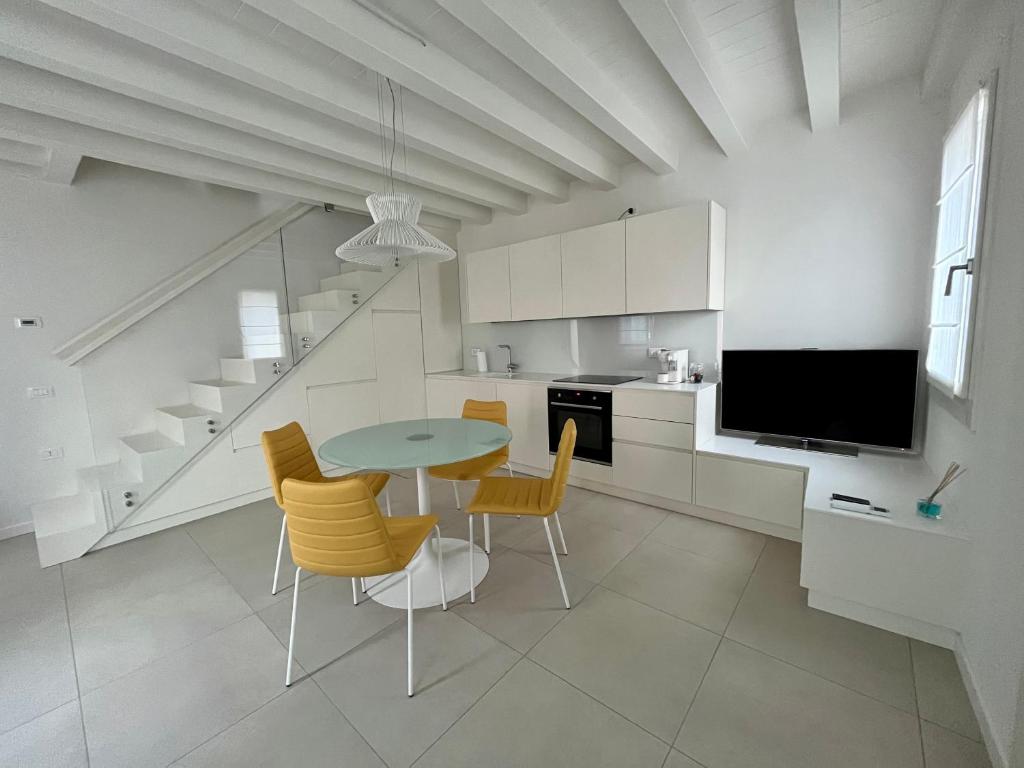 Il comprend une cuisine avec une table et des chaises ainsi qu'une télévision. dans l'établissement Alla Torre 735 - Stay Local Burano, à Burano