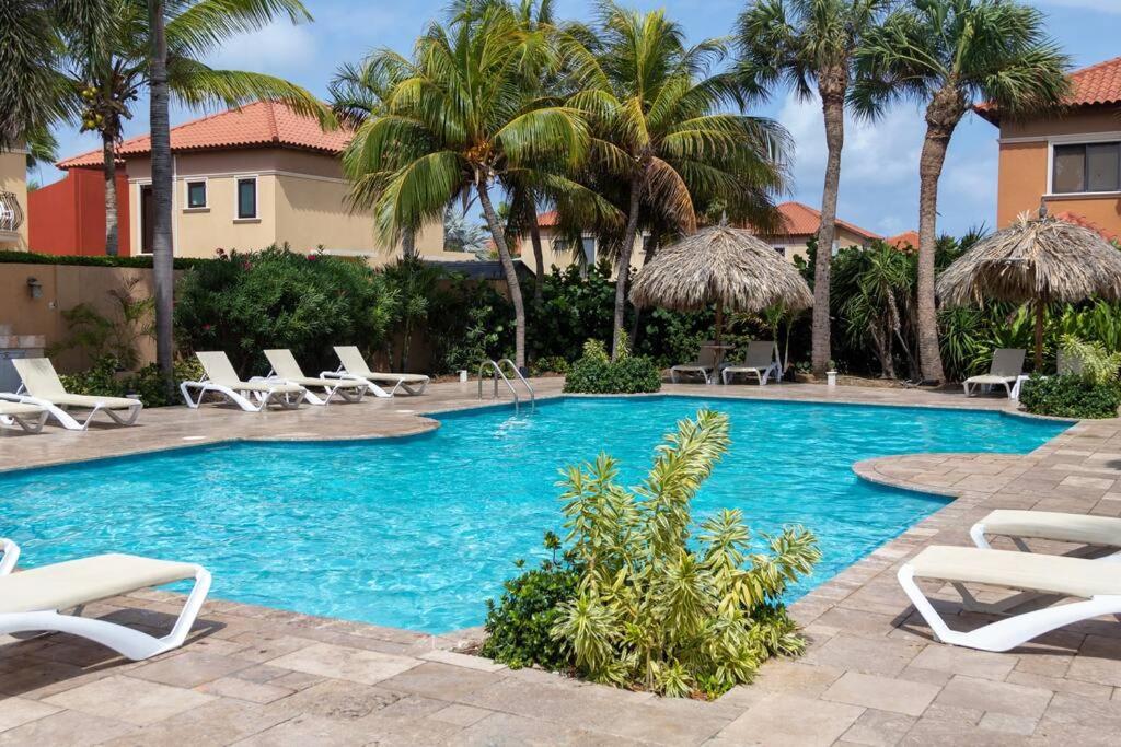 una piscina con sedie a sdraio bianche e palme di New! Cozy 1 Bedroom Condo- Gold Coast, Noord ARUBA a Palm Beach