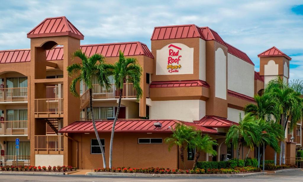 a hotel building with palm trees in front of it at Red Roof Inn PLUS+ & Suites Naples Downtown-5th Ave S in Naples