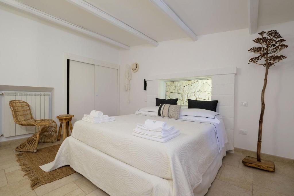a white bedroom with a white bed and a chair at Trullo Natù in Alberobello