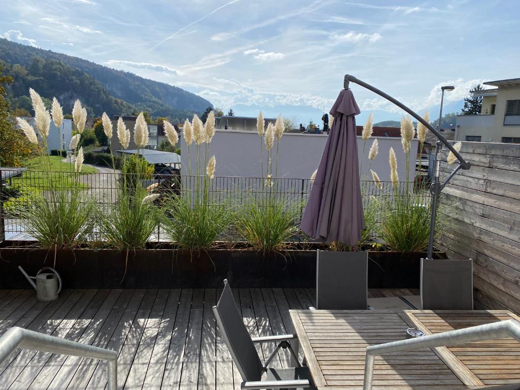 eine Terrasse mit einem Sonnenschirm und Stühlen auf einer Terrasse in der Unterkunft Terrassenwohnung in Götzis in Götzis