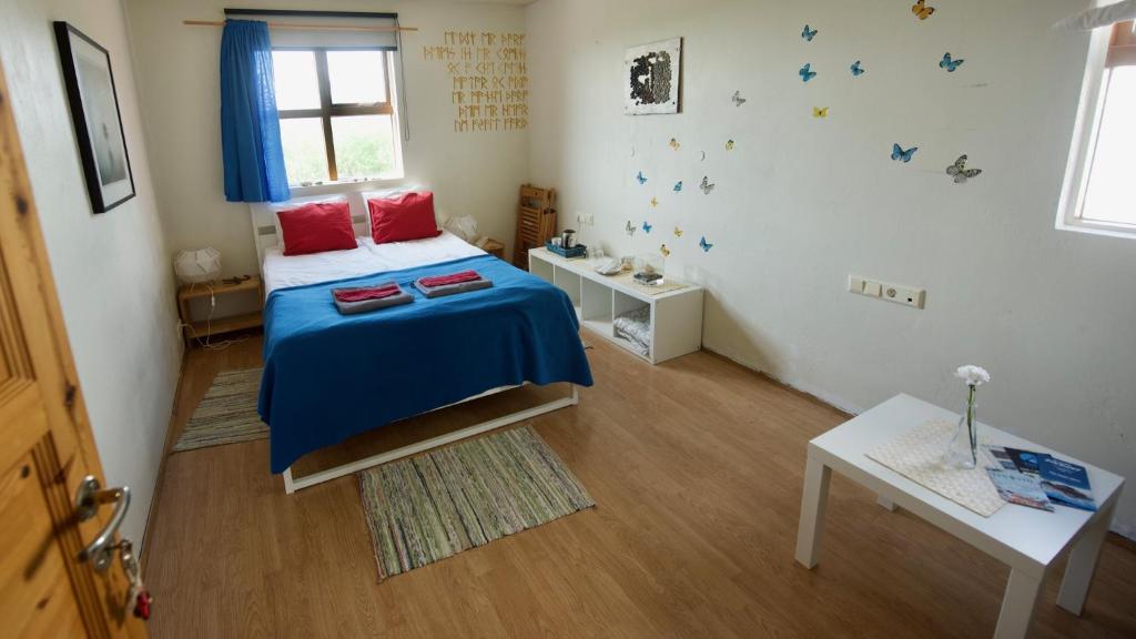 Schlafzimmer mit einem Bett mit blauer Bettwäsche und einem Fenster in der Unterkunft Dynjandi Guesthouse in Höfn