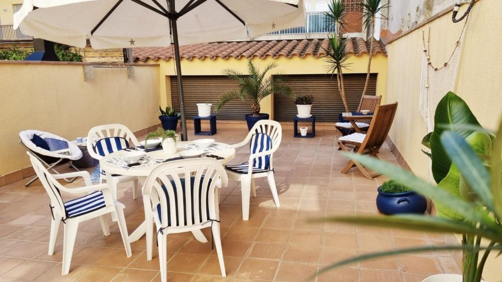 eine Terrasse mit einem Tisch, Stühlen und einem Sonnenschirm in der Unterkunft Costa Brava-St Antoni de Calonge apartament per parelles i famílies petites in Calonge