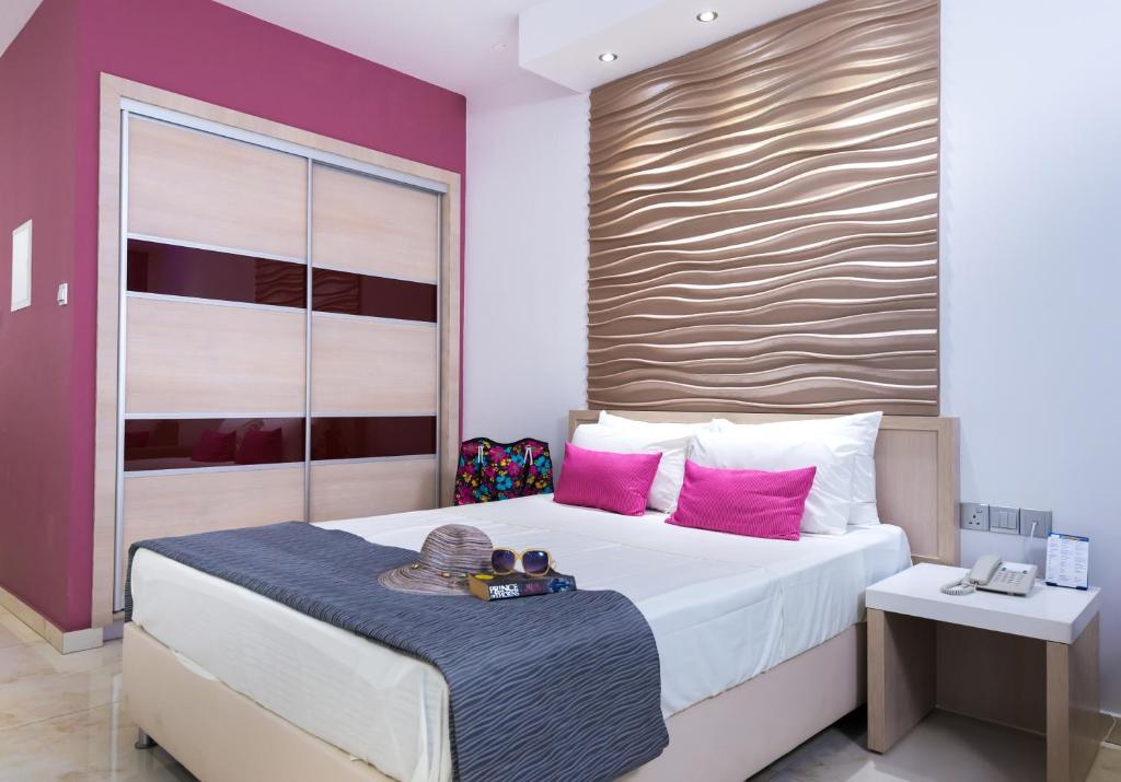a bedroom with a large bed with pink pillows at Loutsiana Deluxe Apts in Ayia Napa