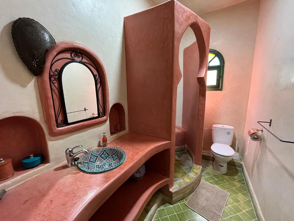 ein Bad mit einem Waschbecken, einem Spiegel und einem WC in der Unterkunft Villa nouran in Ghazoua