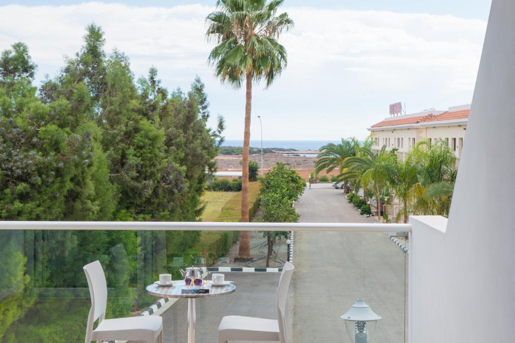 a balcony with a table and chairs and a palm tree at Loutsiana Deluxe Apts in Ayia Napa