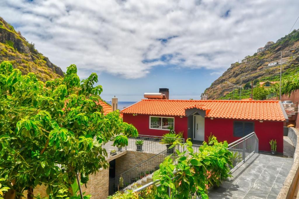 a red house on the side of a mountain at Casa da Praia, a Home in Madeira in Ribeira Brava