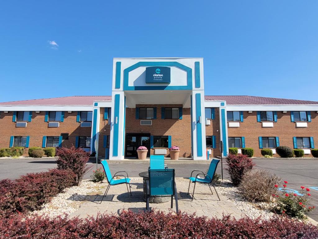 a building with three chairs and a table in front of it at Clarion Pointe Harrodsburg-Danville in Harrodsburg