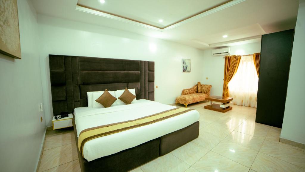 a bedroom with a large bed and a chair at 247 Luxury Hotel & Apartment Ajah in Lekki