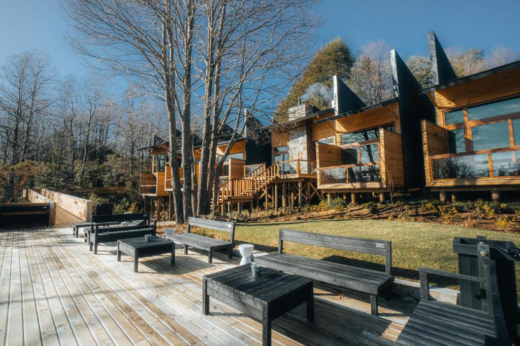a group of benches sitting on a deck in front of a log cabin at NI-NEWEN Hotel &amp; Lodge in Pucón