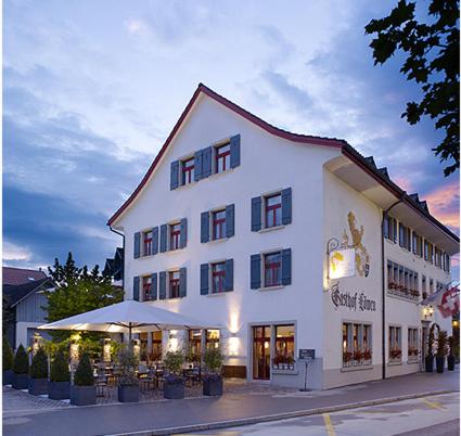 a large white building with tables and chairs in front of it at Gasthof Löwen in Bubikon