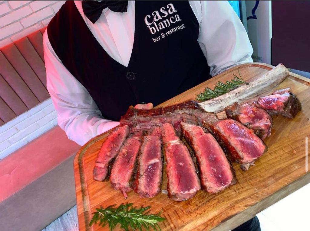 a woman holding a cutting board with a bunch of meat at Vila Casablanca - Boutique Hotel & Restaurant in Shkodër