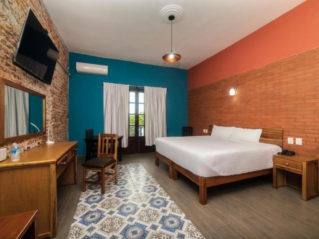 Hotel Meson del Barrio في فيراكروز: غرفة نوم بسرير ومكتب وتلفزيون