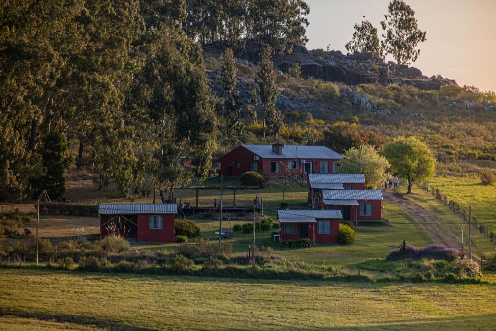 un grupo de graneros rojos en un campo al lado de una colina en Cabañas Los Pioneros en Tandil