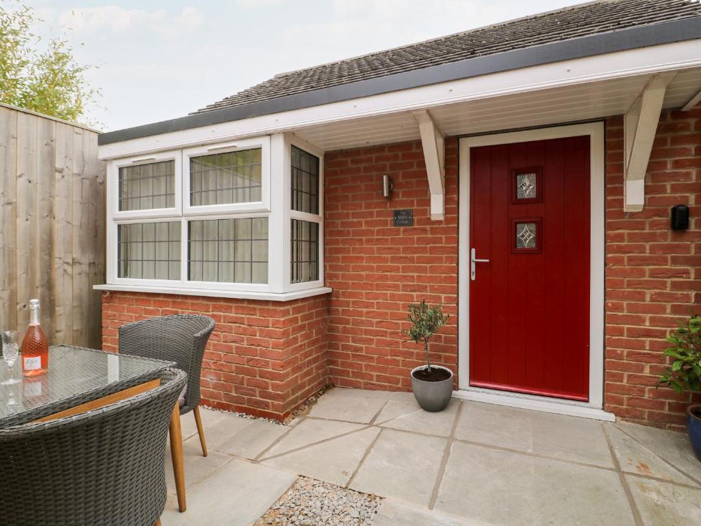 a brick house with a red door and a table at Robin Cottage in Beverley