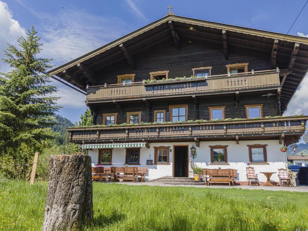 ein großes Holzhaus mit Baumstumpf davor in der Unterkunft Weberhof Top 2 in Brixen im Thale
