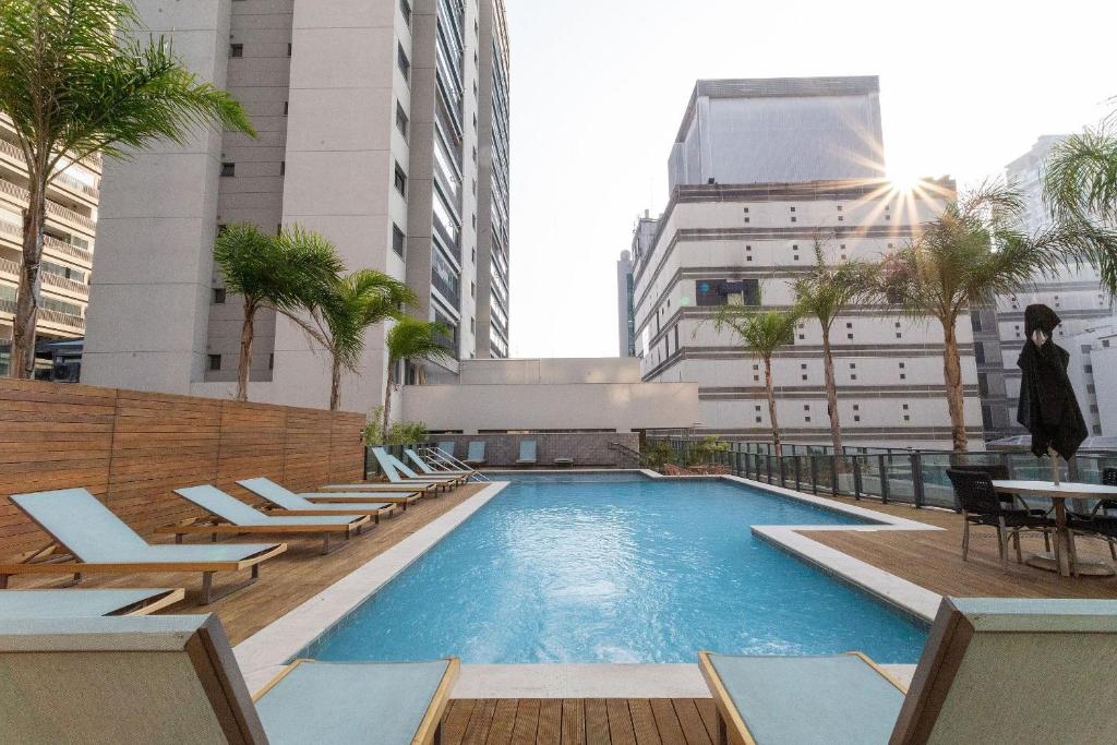 a swimming pool with lounge chairs and a building at Facto Bela Vista - Studios por temporada in Sao Paulo