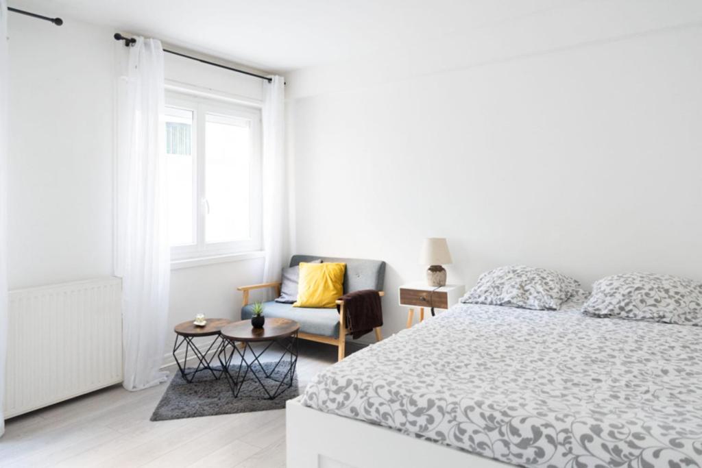 a white bedroom with a bed and a chair at Spacious studio in the center of Montmartre in Paris