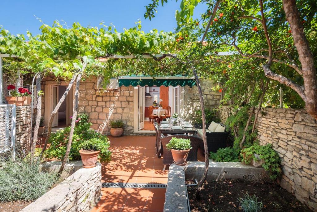 einen Garten mit einem Tisch und einem Bogen mit Pflanzen in der Unterkunft Seaside house for families with children Sutivan, Brac - 20131 in Sutivan