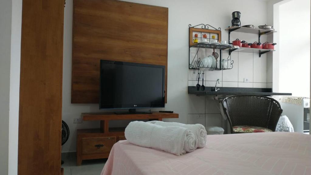 1 dormitorio con 1 cama y mesa con TV en Refúgio Ouro Fino Kitnets Casas e Apartamentos, en Paraty