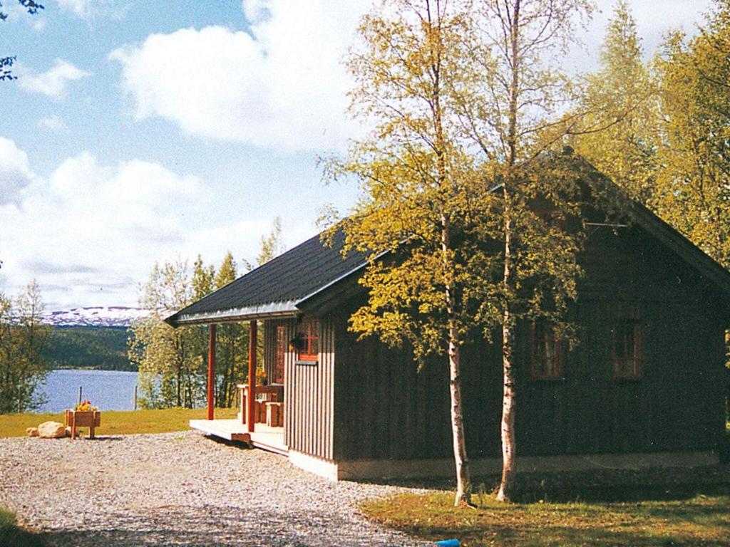 a small cabin with a tree in front of a lake at 6 person holiday home in Nordli in Holand