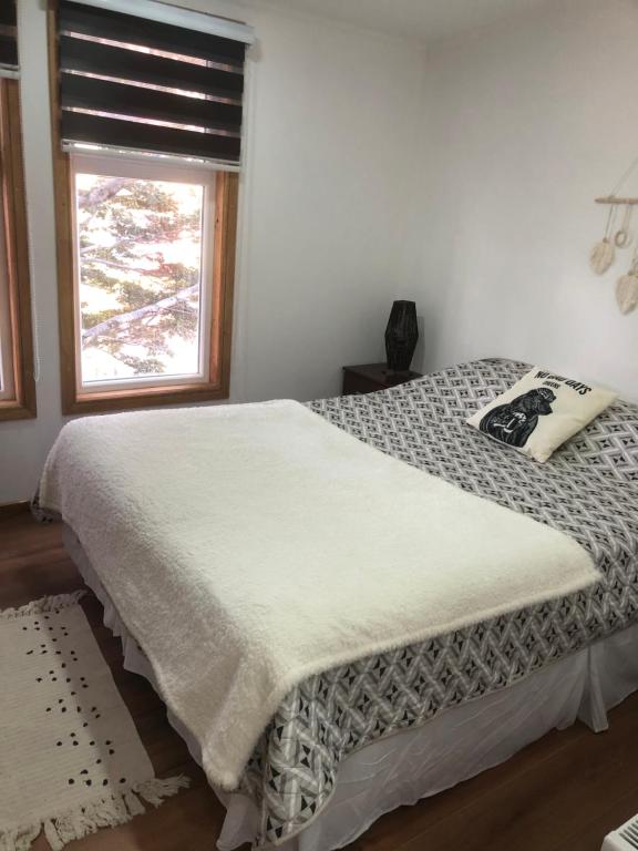 Schlafzimmer mit einem großen Bett und einem Fenster in der Unterkunft Departamentos Carrera Nro 1 in Punta Arenas